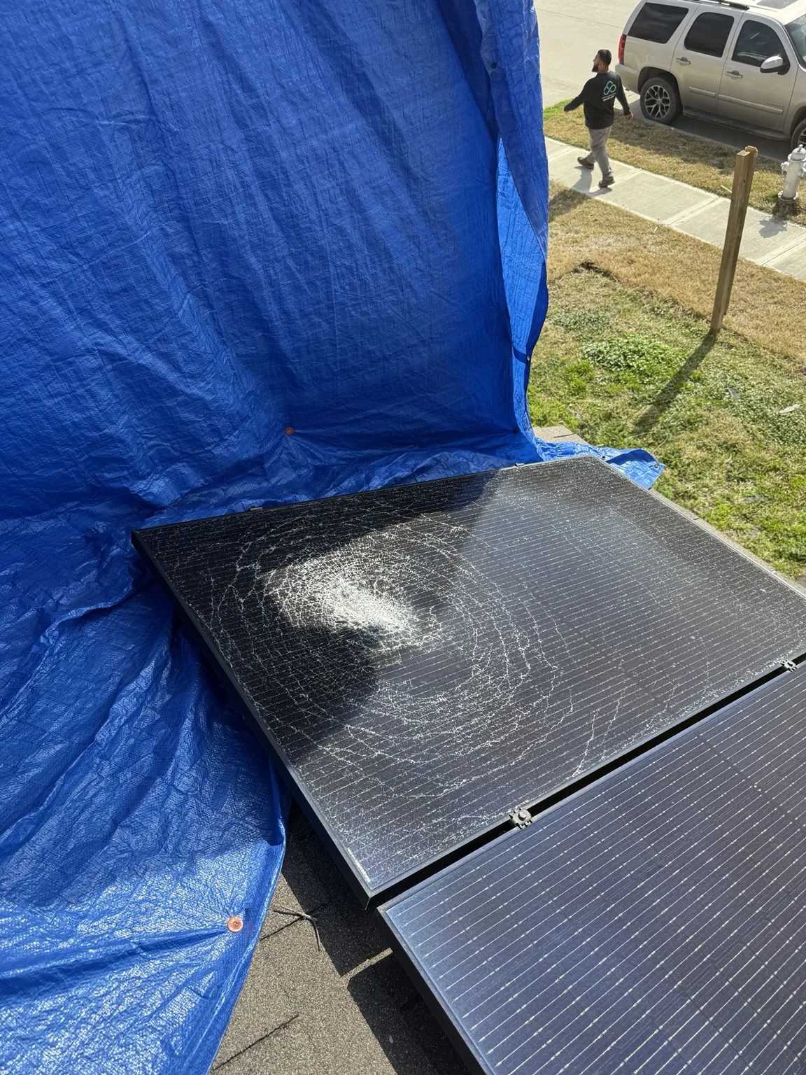 A solar panel with cracked glass beside a blue tarp