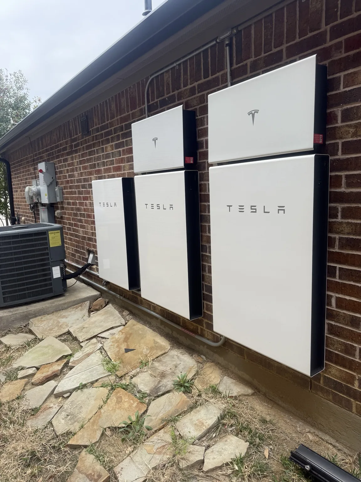 Tesla battery equipment mounted on a brick exterior wall