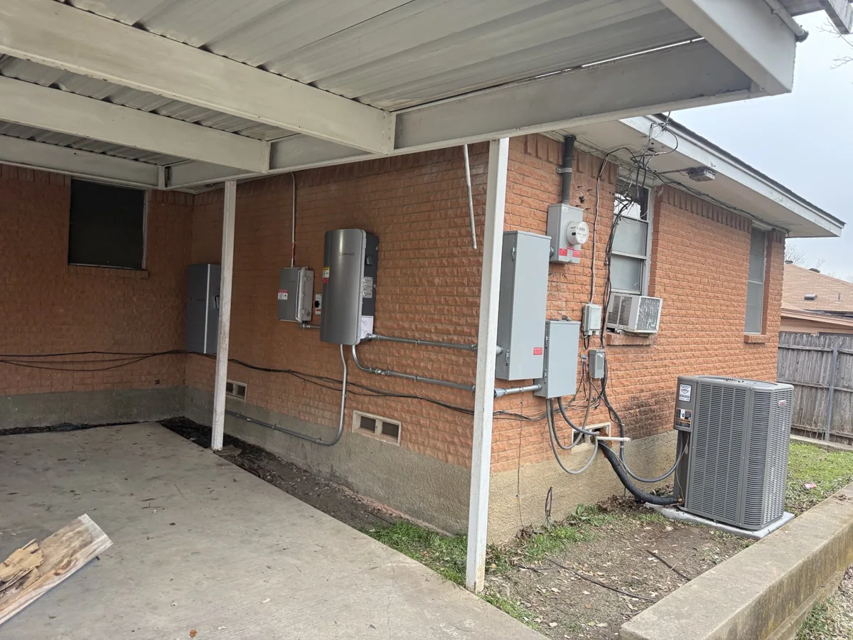 Solar electrical equipment installed on a brick exterior under a patio roof