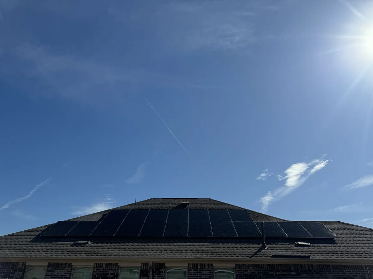 A residential rooftop solar array viewed from the yard