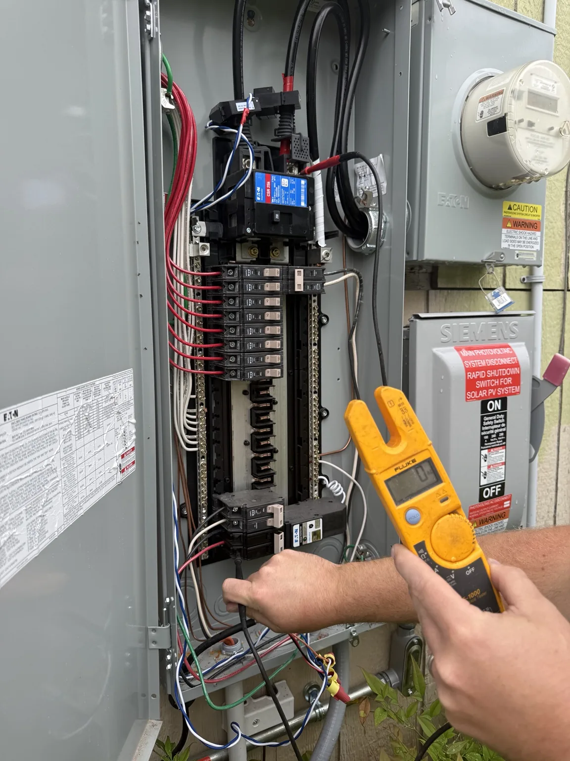 Technician using a meter at an open electrical panel
