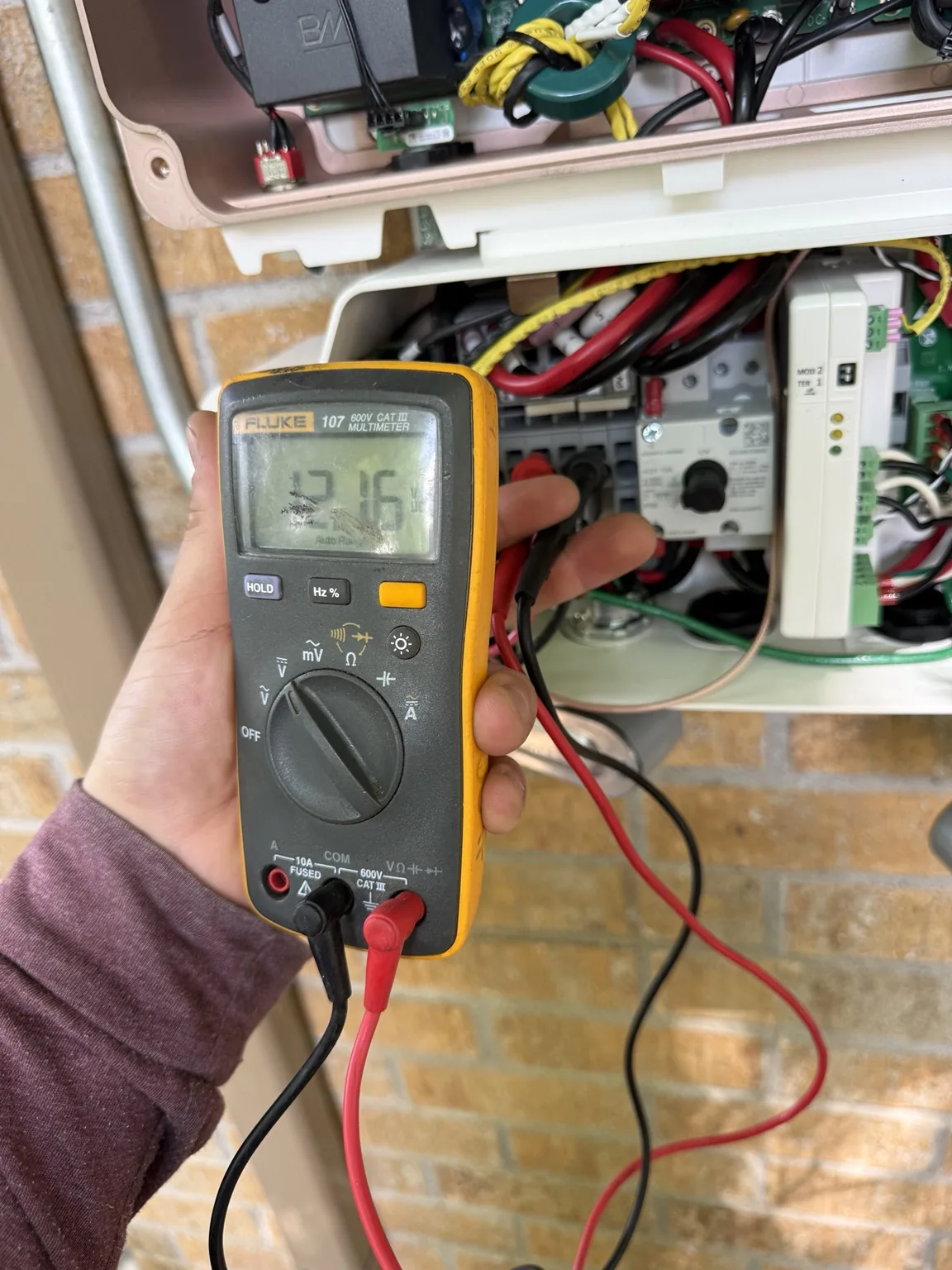 Multimeter beside open solar electrical equipment