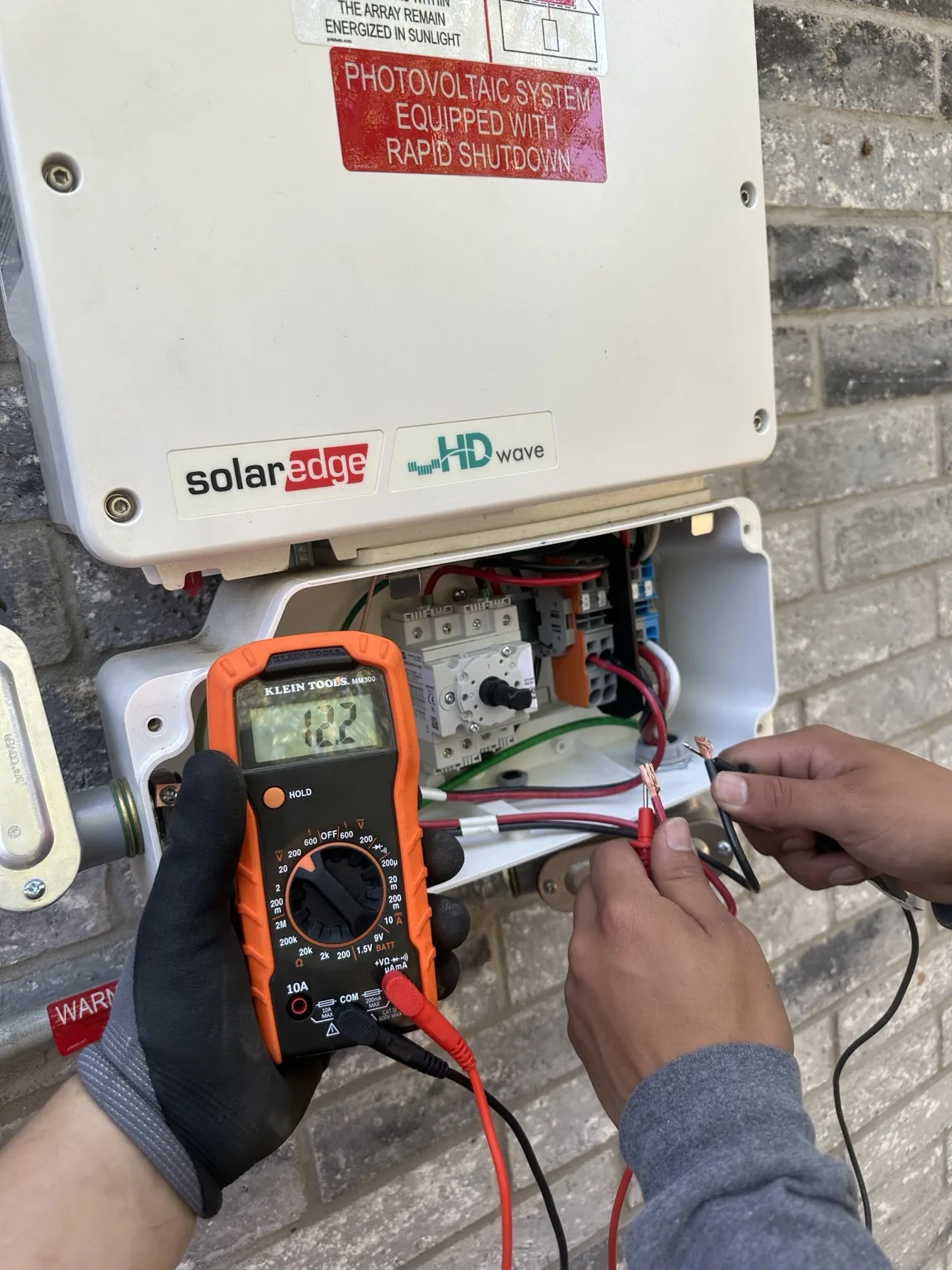 Technician using a meter to test SolarEdge inverter equipment
