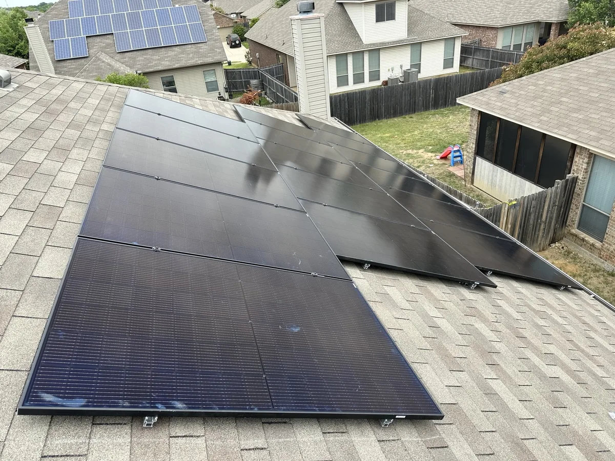 Dark solar panels mounted above a residential shingle roof